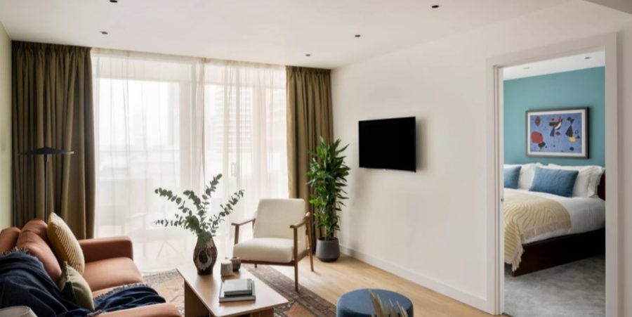 Interior of a contemporary apartment showcasing a couch, a chair, and a television in a cozy arrangement.